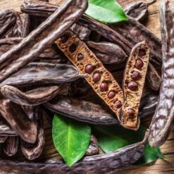 Amaru Unnimaffissu - L'amaro Siciliano -Food Series Store carob pods and carob beans on the wooden table 1032651457